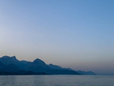 Dağların ve sakin suların ardında inanılmaz güzel bir deniz batımı. Gökyüzünün çok güzel bir rengi var, güneş dağların ardında batıyor. Hindi, Ege Denizi. Yüksek kalite fotoğraf