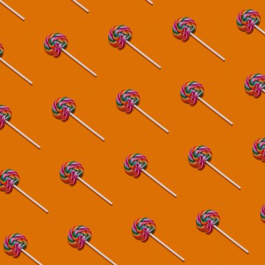  Turuncu renkli arka planda lolipopların deseni. Tatlı şeker konsepti. Renkli yemekler. Yüksek kalite fotoğraf