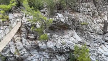 Nehirli bir dağ geçidi üzerindeki asma köprü. Dağlarda turizm. Yüksek kalite 4k görüntü