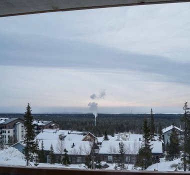 Kuzeyde kış sükuneti yumuşak bir akşam gökyüzünün altında huzurlu, karlı bir köy, uzaktan yükselen dumanla mükemmel bir kış kaçışı..