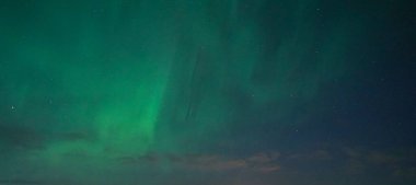 Karanlık ufukta sersemletici yeşil aurora borealis parlak kuzey ışıkları yıldızlı gece gökyüzünde dans ederek büyüleyici bir doğal fenomen yaratıyor. Seyahat için ideal, doğa..