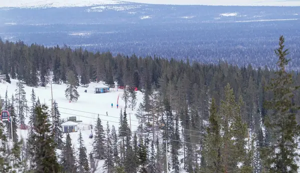 Karlı Orman ve Dağların Ortasındaki Kayak Merkezi sık yeşil ağaçlar ve uzak dağlarla çevrili bir kayak merkezinin nefes kesici kış manzarası. Seyahat ve macera için ideal.