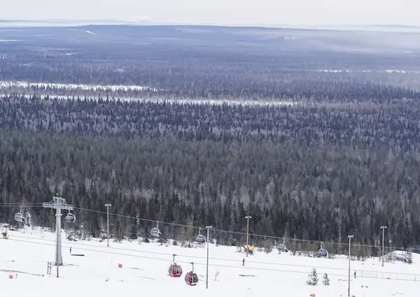 Karlı yamaçların ve ormanların üzerinde kayak kaldırma... arka planda geniş bir orman bulunan karlı yamaçların üzerinde bir kayak kaldırma alanı. Kış sporları, seyahat ve doğa kavramları için mükemmel..