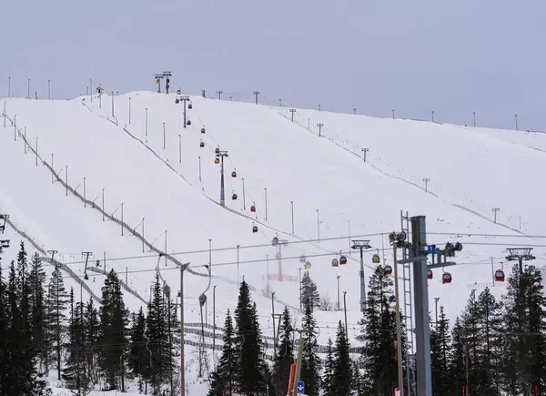 Sandalyeleri ve yamaçları olan karlı bir kayak merkezi kar dağlarında kayakçıları taşıyan teleferikli bir kayak merkezinin kış manzarası. Kış sporları, seyahat ve tatil yerleri için mükemmel..