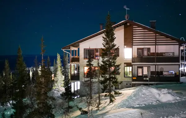 Karlı kış gecelerinde parlayan modern dağ evi yıldızlı bir gökyüzünün altında karlı ağaçların arasına kurulmuş sıcak ışıklarla aydınlatılmış şık bir dağ evi. Doğada mükemmel bir kış kaçamağı.
