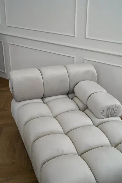 Şık minimalist bir odada yumuşak yastıklı lüks kadife kanepe. Beyaz panelli duvarlar ve ahşap döşeme zarif, çağdaş bir konfor atmosferi yaratır..