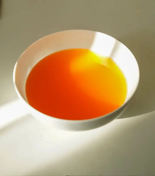 Beyaz bir masanın üzerinde sabah güneşiyle yıkanmış canlı bir bitki çayı. Doğal renk kontrastı ve sakinleştirici atmosferi olan minimalist bileşim.