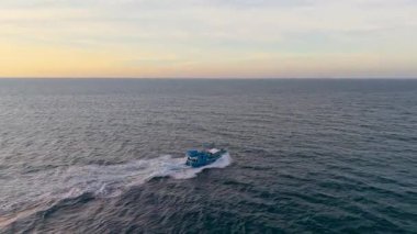 Vietnam balıkçı teknesinin insansız hava aracı görüntüsü. Parlak gökyüzü altında tropik deniz dalgaları arasında hızla ilerliyor. Yüksek kalite kraliyet malı. En iyi balıkçı teknesi sakin okyanus dalgalarıyla kıyıya doğru yol alıyor.