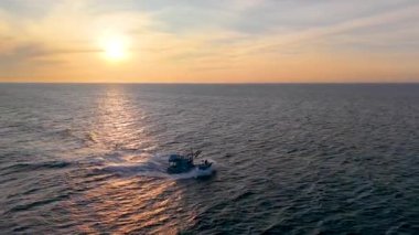 Vietnam balıkçı teknesinin hava aracı görüntüsü, tropikal deniz dalgaları üzerinde gündoğumunda gökyüzü altında hareket ediyor. Yüksek kalite kraliyet malı. En iyi balık stoğu. Sakin okyanus dalgaları ve kültürel deniz manzarası ile açık denizlere doğru gidiyor.