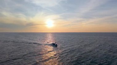 Vietnam balıkçı teknesinin hava aracı görüntüsü, tropikal deniz dalgaları üzerinde gündoğumunda gökyüzü altında hareket ediyor. Yüksek kalite kraliyet malı. En iyi balık stoğu. Sakin okyanus dalgaları ve kültürel deniz manzarası ile açık denizlere doğru gidiyor.