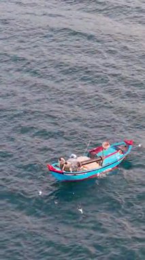 Okyanustaki balıkçı teknesinin havadan görünüşü, ağlarla çalışan balıkçılar, geleneksel geçim kaynakları ve Vietnam kıyılarının otantik yaşam tarzı. Balıkçılar denizde ahşap balıkçı teknesine ağlar çekiyor. 