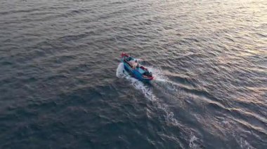 Vietnam balıkçı teknesinin insansız hava aracı görüntüsü. Parlak gökyüzü altında tropik deniz dalgaları arasında hızla ilerliyor. Yüksek kalite kraliyet malı. En iyi balıkçı teknesi sakin okyanus dalgalarıyla kıyıya doğru yol alıyor.