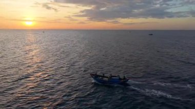 Vietnam balıkçı teknesinin hava aracı görüntüsü, tropikal deniz dalgaları üzerinde gündoğumunda gökyüzü altında hareket ediyor. Yüksek kalite kraliyet malı. En iyi balık stoğu. Sakin okyanus dalgaları ve kültürel deniz manzarası ile açık denizlere doğru gidiyor.