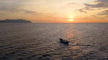 Okyanusta tekneyle gün doğumu balıkçılık sahnesi, sıcak altın ışık, sakin dalgalar, deniz manzarası seyahat geçmişi ve geleneksel deniz kültürü..