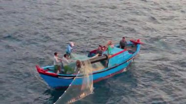 Okyanustaki balıkçı teknesinin havadan görünüşü, ağlarla çalışan balıkçılar, geleneksel geçim kaynakları ve Vietnam kıyılarının otantik yaşam tarzı. Balıkçılar denizde ahşap balıkçı teknesine ağlar çekiyor. 