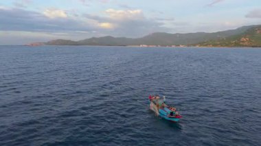 Okyanustaki balıkçı teknesinin havadan görünüşü, ağlarla çalışan balıkçılar, geleneksel geçim kaynakları ve Vietnam kıyılarının otantik yaşam tarzı. Balıkçılar denizde ahşap balıkçı teknesine ağlar çekiyor. 