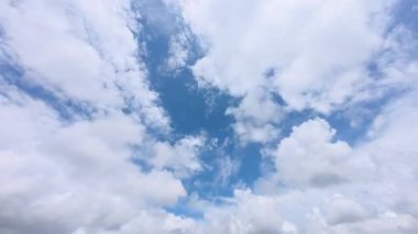 Güneşli bir günde açık mavi bir gökyüzünde süzülen tüylü bulutların hızlandırılması ya da zamanlaması. Parlak ve huzurlu hava manzarası, beyaz bulutlar canlı mavi bir gökyüzünde hızla hareket ediyor. 