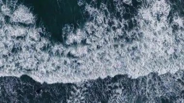 Aerial view, top view of sea waves on beach sand. Royalty high-quality free best stock of turquoise colored breaking wave seascape on the beach. Wave crashing, splash