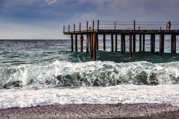 Storm in the Mediterranean Sea, Turkey, strong waves near the old wooden pier.