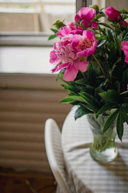 Masanın üzerinde bir vazoda pembe peonies buket.