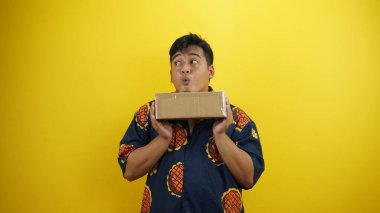 Genç Asyalı bir adamın portresi gömlek ve gözlük takıyor ve sarı arka planda şaşırmış bir yüz var.