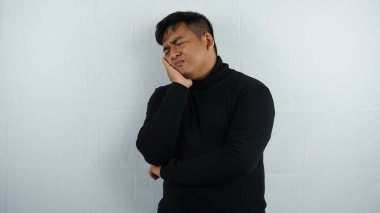 Genç yakışıklı Asyalı, el ağrısı ve baş ağrısı olan genç bir adam..