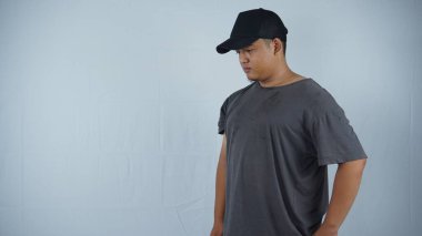 Asyalı adam tişört ve şapka giyiyor.
