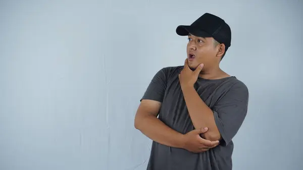 stock image asian muslim man wearing a white t - shirt with a surprised expression on white isolated background