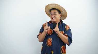 Genç Asyalı güneş gözlüğü takıyor ve beyaz arka planda izole edilmiş parmakları işaret ediyor.