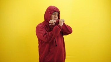 Kırmızı arka plana karşı ciddi bir jesti olan genç Latin bir adam.