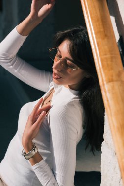 Neşeli, mutlu, güzel, dişlek bir kadının fotoğrafı. Güneşin tadını çıkaran güneş gözlüğü takıyor. Gömlekli şehir dışında.