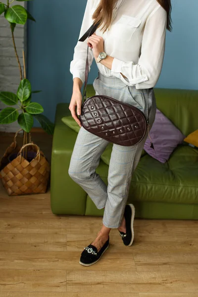 一个有花纹的棕色皮包的女人 穿着灰色格子裤子 头戴白色衬衫 头戴手提包的女孩 — 图库照片
