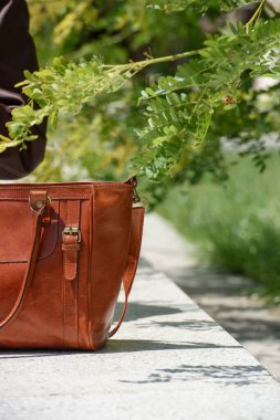 close-up photo of luxury orange leather bag on a white marble. outdoors photo
