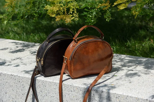 Two small leather bags, dark and light brown colored. round old-fashioned leather bags. outdoors photo.
