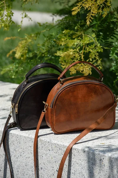 Two small leather bags, dark and light brown colored. round old-fashioned leather bags. outdoors photo.