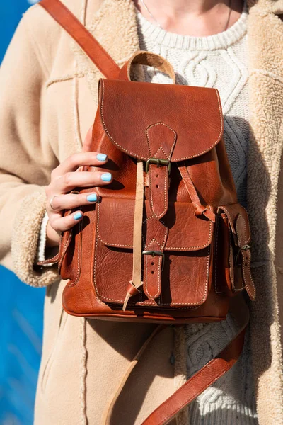 Woman with a brown leather backpack with antique and retro look. Outdoors photo.