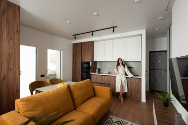 Güzel bir kadın mutfakta elinde bir fincan çayla ayakta duruyor. tadilattan sonra daire.