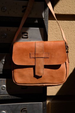 close-up photo of yellow small craft leather bag on a postbox. street photo.