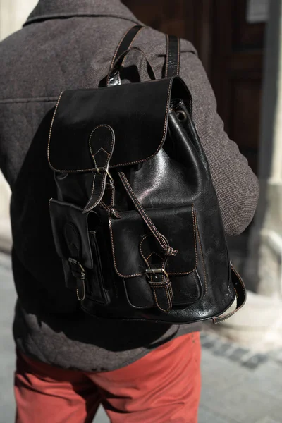 man with a black leather backpack with antique and retro look. Outdoors photo.