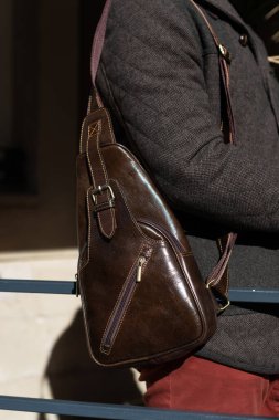 part photo of a man with brown leather bag . outdoors photo