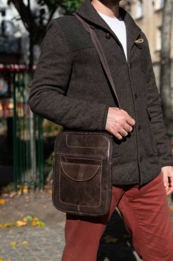 part photo of a man with brown leather bag . outdoors photo