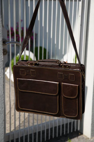 brown mens shoulder leather bag for a documents and laptop. Outdoors photo.
