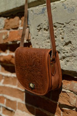 İşlenmiş desenli küçük kahverengi kadın deri çantası. sokak fotoğrafı