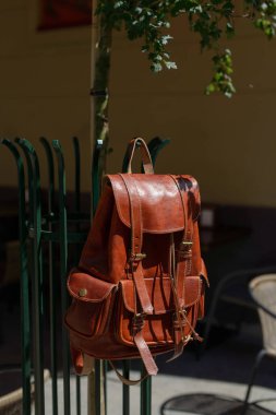 Orange leather oldfashioned backpack on a metal grid. outdoors