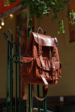 Orange leather oldfashioned backpack on a metal grid. outdoors