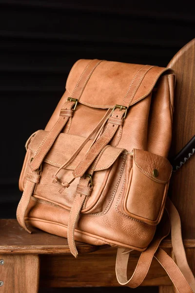 photo of a light brown leather backpack with antique and retro look. indoors photo.