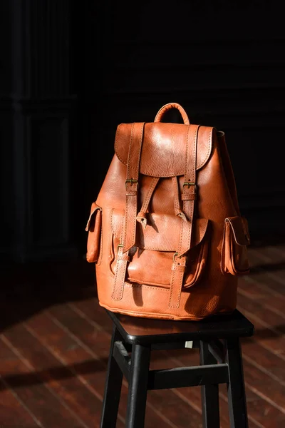 photo of a orange leather backpack with antique and retro look. indoors photo.