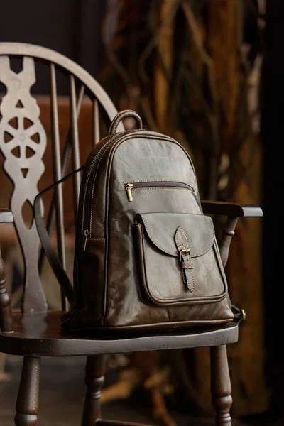 Brown leather backpack on the stylish chair. indoor photo