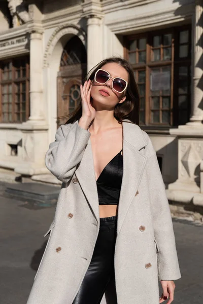 Street style, autumn, spring fashion concept: fashionable woman wearing luxury beige coat, a top with razors and sunglasses