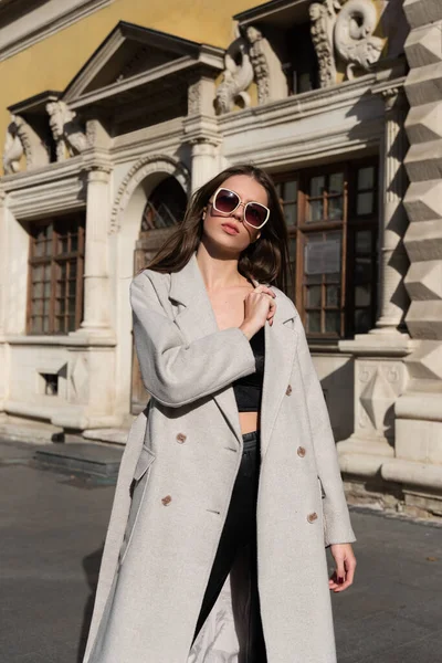 Street style, autumn, spring fashion concept: fashionable woman wearing luxury beige coat, a top with razors and sunglasses